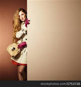 Photo young beautiful woman in a raincoat in interior. Conceptual fashion. Text background