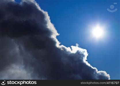 Photograph showing the sun and blue sky emerging from behind a storm cloud.