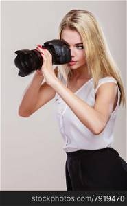Photographer girl shooting images. Attractive blonde woman taking photo with camera.