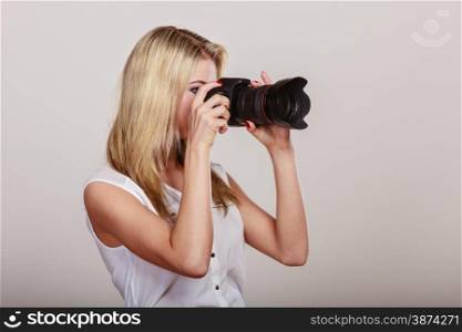 Photographer girl shooting images. Attractive blonde woman taking photos with camera.