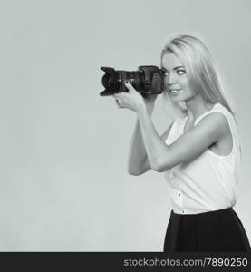 Photographer girl shooting images. Attractive blonde woman taking photos with camera. Black and white photo