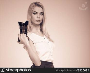 Photographer girl shooting images. Attractive blonde woman taking photos with camera. Filtered photo
