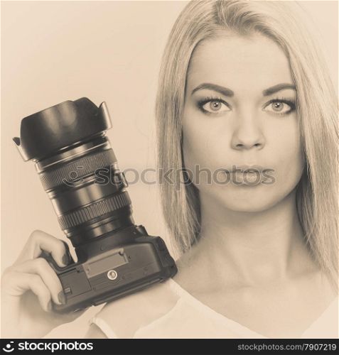 Photographer girl shooting images. Attractive blonde woman taking photos with camera. Filtered photo