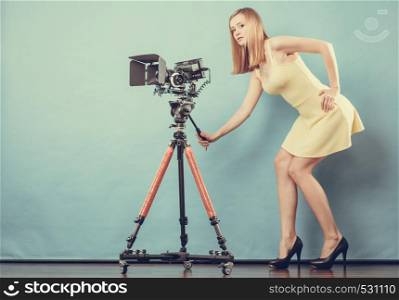 Photographer girl shooting images. Attractive fashionable blonde woman in full length taking photos with camera on blue