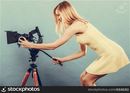Photographer girl shooting images. Attractive fashionable blonde woman taking photos with camera on blue