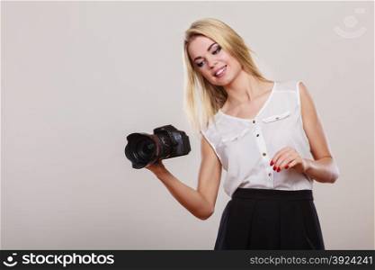 Photographer girl shooting images. Lovely blonde woman with professional camera on gray background
