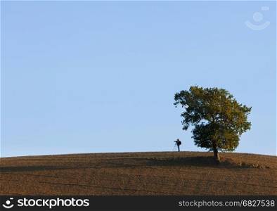 Photographer on the hill over blue sky