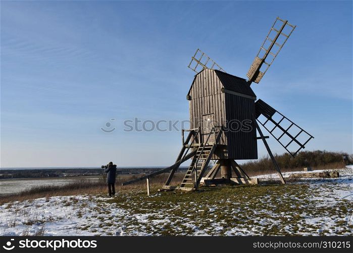 Photographer shoots a winter view by an old windmill in a wintry landscape at the swedish island Oland