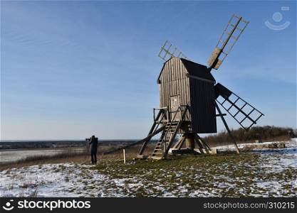 Photographer shoots a winter view by an old windmill in a wintry landscape at the swedish island Oland