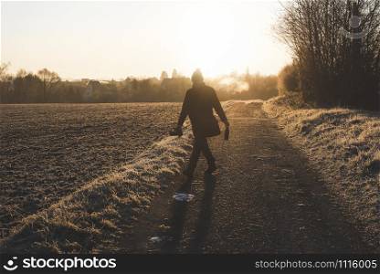 Photographer silhouette wandering at sunrise in winter frost scenery, near Schwabisch Hall, Germany. Man walking on countryside alley on cold morning