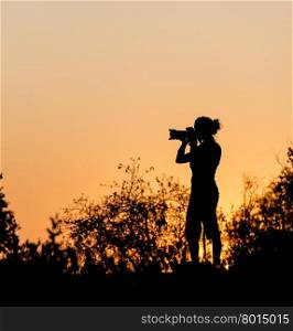Photographer silhouetted against a golden sunset sky in Africa
