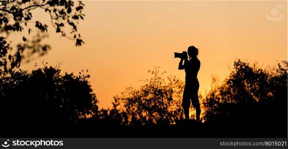 Photographer silhouetted against a golden sunset sky in Africa