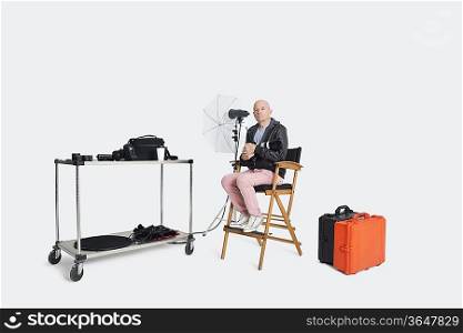 Photographer sitting on director&acute;s chair with equipments in studio