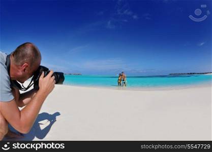 photographer taking photo of models couple on beautiful tropical beach at summer