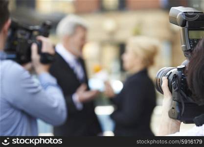 Photographer Taking Pictures Of Female Journalist Interviewing Businessman