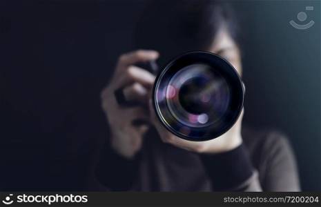 Photographer Taking Self-Portrait. Woman using Camera to Taking Photo. Dark Tone, Front View. Selective focus on Lense. Straight into a Camera
