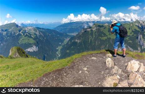 Photographer traveler makes a photo of the alpine valley on a Mannlichen mountain viewpoint, Bernese Oberland Switzerland. Mannlichen viewpoint, Switzerland