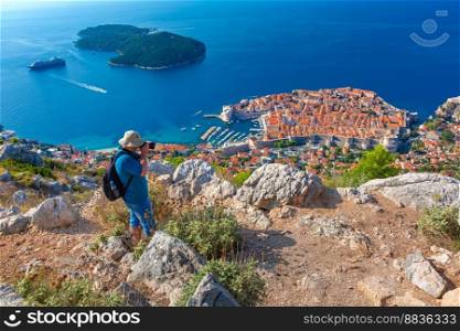 Photographer traveler takes a photo of aerial view of Old Harbour and Fort St Ivana in Dubrovnik, Croatia. Old Harbor of Dubrovnik, Croatia