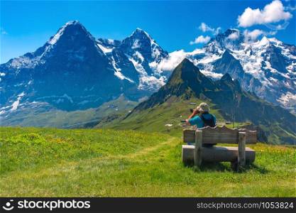 Photographer traveler takes a photo of the alpine valley on a Mannlichen mountain viewpoint, Bernese Oberland Switzerland. Mannlichen viewpoint, Switzerland