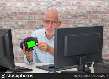 photographer with a camera at office with computer, green screen