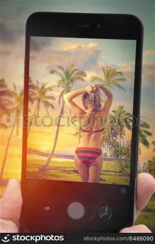 Photographing a blogger on a mobile phone. girl in a swimsuit standing on the beach. palms on the beach of Easter Island.