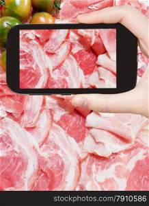 photographing food concept - tourist takes picture of italian prosciutto, pancetta and green tomato on smartphone, Italy