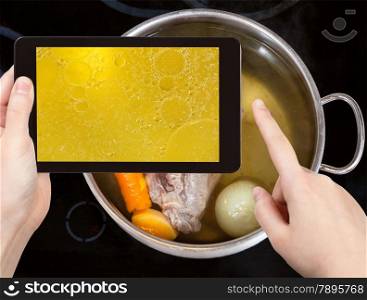 photographing food concept - tourist taking photo of boiling beef broth with with seasoning vegetables on mobile gadget