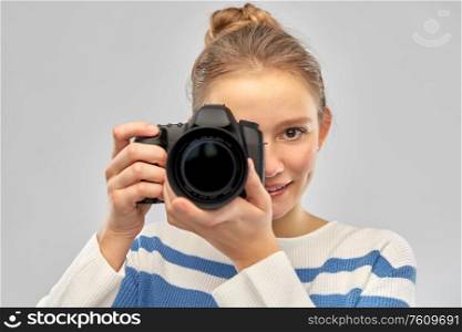 photography and people concept - smiling teenage girl in pullover with digital camera over grey background. smiling teenage girl r with digital camera