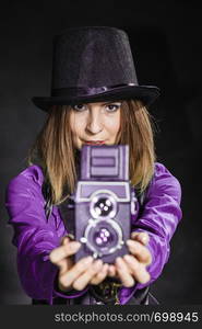 Photography and retro style. Young vintage attractive girl holds old aged camera. Steampunk photographer taking photo.. Steampunk with old retro camera.