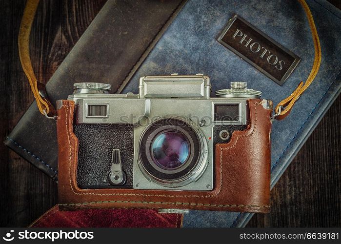 Photography concept background - old retro vintage camera on photo album on grunge wooden texture. Old retro vintage camera on grunge wooden background