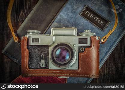 Photography concept background - old retro vintage camera on photo album on grunge wooden texture. Old retro vintage camera on grunge wooden background