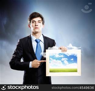 Photography concept. Handsome young man holding frame with pictures