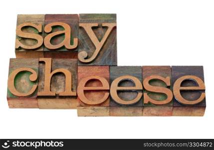 photography concept - say cheese phrase in vintage wooden letterpress printing blocks, stained by color inks, isolated on white