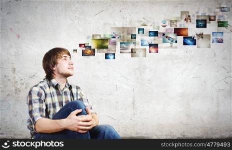 Photography concept. Young man in casual sitting on floor and looking at media photos