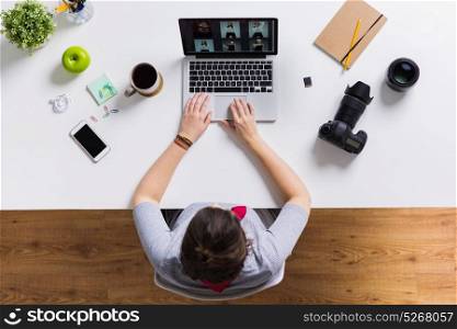 photography, people and technology concept - woman with camera working on laptop at table. woman with camera working on laptop at table