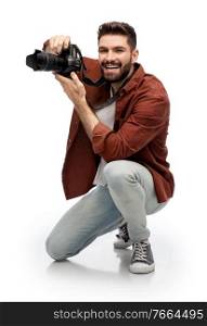 photography, profession and people and concept - happy smiling man or photographer with digital camera staying on one knee and taking picture over white background. smiling man or photographer with digital camera