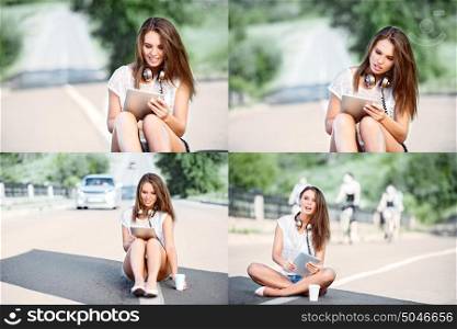 Photoset of a happy young woman sitting on a separating strip, drinking coffee from a takeaway coffee cup, wearing music headphones and buying music on tablet online against road background.