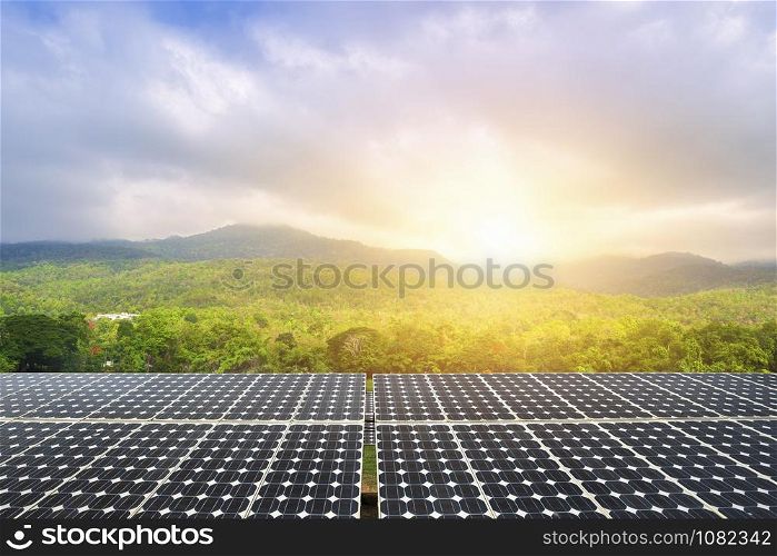 Photovoltaic modules solar power plant with green forested mountain and blue sky sunset background, Alternative energy concept.
