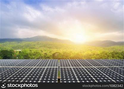 Photovoltaic modules solar power plant with green forested mountain and blue sky sunset background, Alternative energy concept.