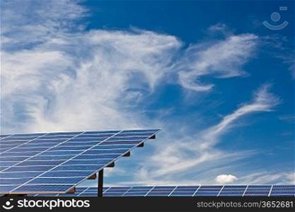 Photovoltaic panels in a solar power plant over a deep blue sky.