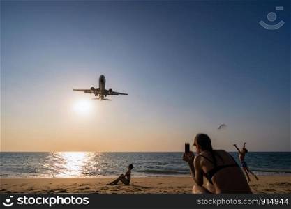 PHUKET, Thailand - FEB 5, 2018 : Undefined Travelers looking and talking photo to the Airplane landing closely at the sea beach beside the phuket international airport on Febuary 5, 2018, Thailand.