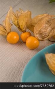 Physalis fruits on blue ceramic plate and a wooden table.