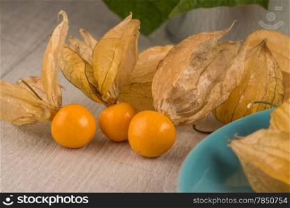 Physalis fruits on blue ceramic plate and a wooden table.