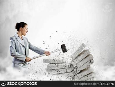 Physical strength. Image of businesswoman breaking bricks with hammer