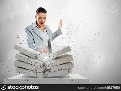 Physical strength. Image of businesswoman breaking bricks with hand