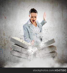 Physical strength. Image of businesswoman breaking bricks with hand