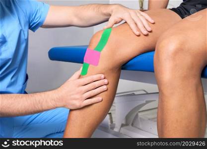 Physical therapist applying kinesio tape on male patient knee. Kinesiology, physical therapy, rehabilitation concept. close up. High quality photo. Physical therapist applying kinesio tape on male patient knee. Kinesiology, physical therapy, rehabilitation concept. close up