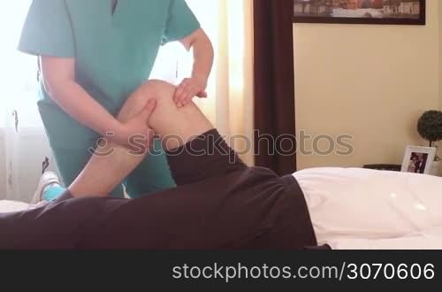 Physical therapist giving a knee massage to young man.
