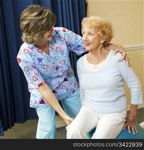 Physical therapist helps a senior woman exercise using a pilates ball.