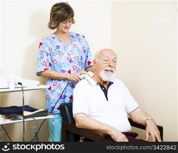 Physical therapist in chiropractic office gives ultrasound therapy to a senior man with neck pain.